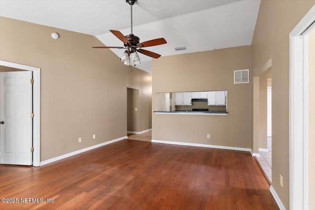 unfurnished living room with ceiling fan, wood finished floors, baseboards, and high vaulted ceiling