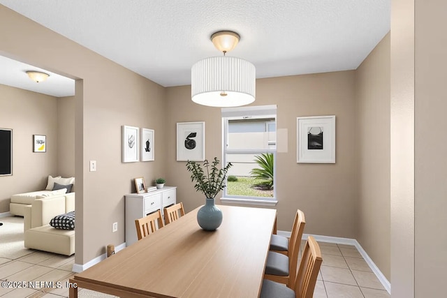 dining room with light tile patterned flooring, baseboards, and a textured ceiling