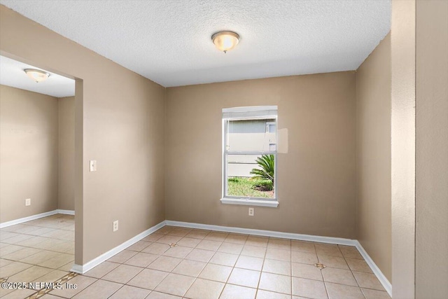 unfurnished room featuring light tile patterned floors, a textured ceiling, and baseboards
