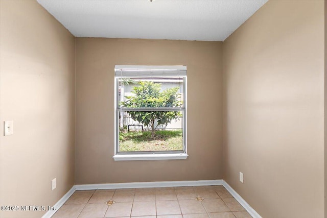 unfurnished room featuring light tile patterned flooring and baseboards