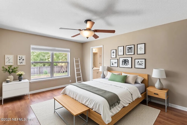 bedroom featuring baseboards, wood finished floors, a ceiling fan, and ensuite bathroom