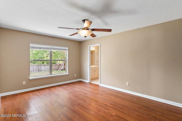 spare room featuring wood finished floors, baseboards, a ceiling fan, and a textured ceiling