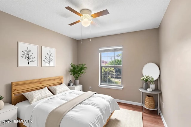 bedroom with wood finished floors, baseboards, and a ceiling fan