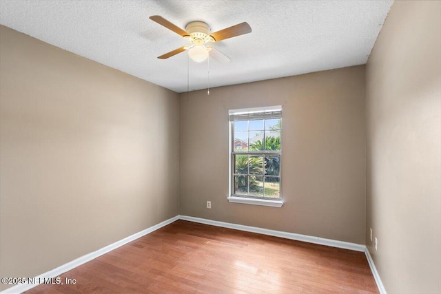 unfurnished room with wood finished floors, baseboards, a ceiling fan, and a textured ceiling