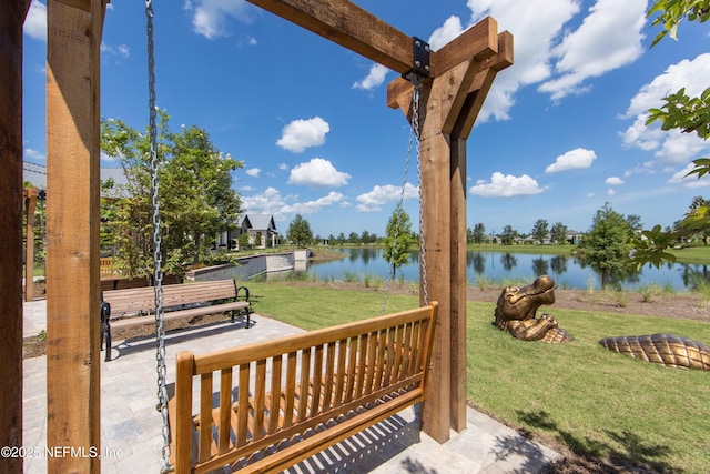 view of property's community featuring a water view, a lawn, and a patio area