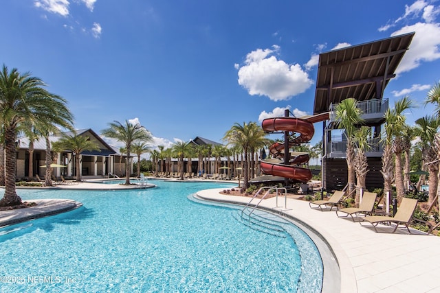 community pool featuring a water slide and a patio area