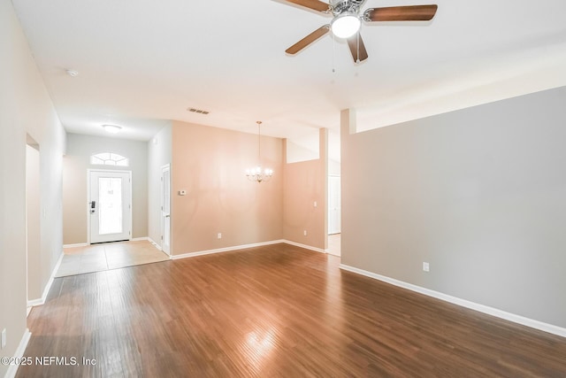 empty room featuring a chandelier, ceiling fan, wood finished floors, and baseboards
