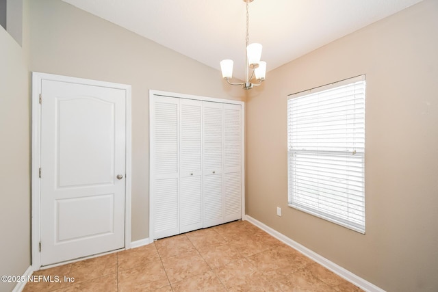 unfurnished bedroom featuring a chandelier, multiple windows, a closet, baseboards, and vaulted ceiling