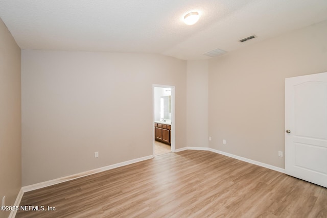 spare room with light wood-type flooring, baseboards, and lofted ceiling