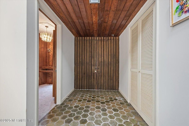 7868 Woodsdale Ln, Jacksonville, FL 32256 - corridor with wooden ceiling, dark stone finish flooring, a chandelier, baseboards, and dark colored carpet