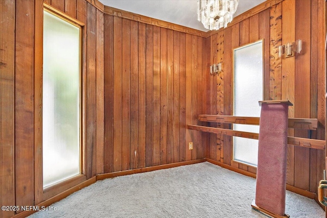 7868 Woodsdale Ln, Jacksonville, FL 32256 - empty room featuring plenty of natural light, wood walls, a chandelier, and carpet floors