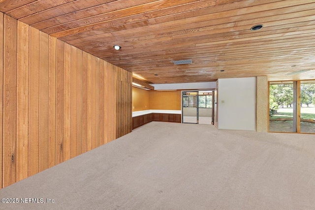 7868 Woodsdale Ln, Jacksonville, FL 32256 - carpeted empty room featuring wooden ceiling, wood walls, and healthy amount of natural light