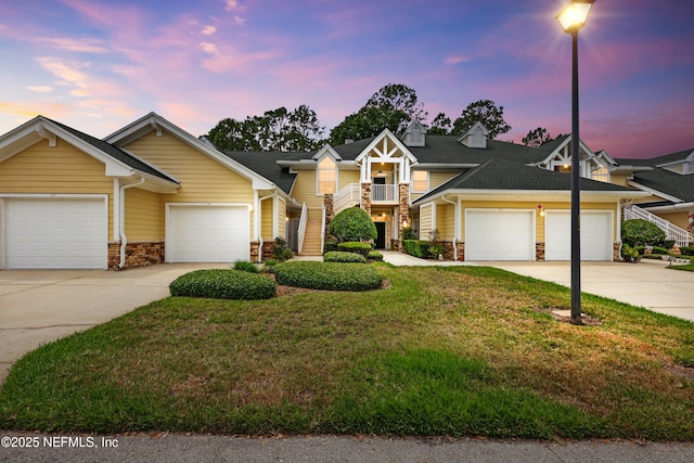 view of front of home with stone siding, a front lawn, driveway, a garage, and stairs