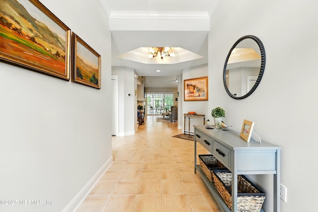 corridor with crown molding, baseboards, a chandelier, a tray ceiling, and light tile patterned floors