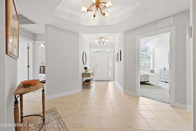 foyer with a chandelier, healthy amount of natural light, light tile patterned floors, baseboards, and crown molding