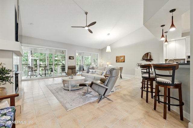 living room with a ceiling fan, light tile patterned floors, high vaulted ceiling, and baseboards