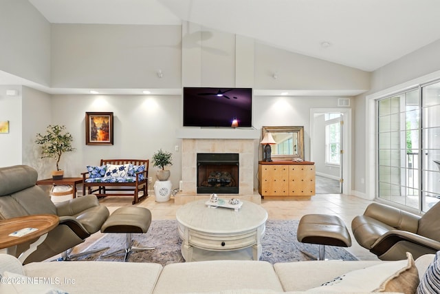 living area with vaulted ceiling and a tiled fireplace