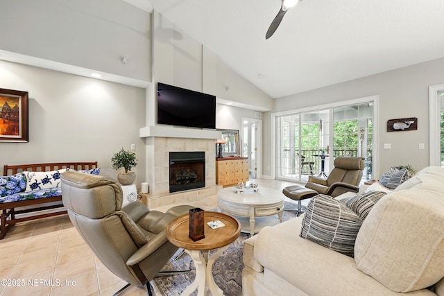 living room featuring a tiled fireplace, light tile patterned floors, high vaulted ceiling, and a ceiling fan