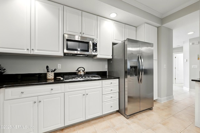 kitchen with stainless steel appliances, ornamental molding, white cabinetry, light tile patterned floors, and baseboards