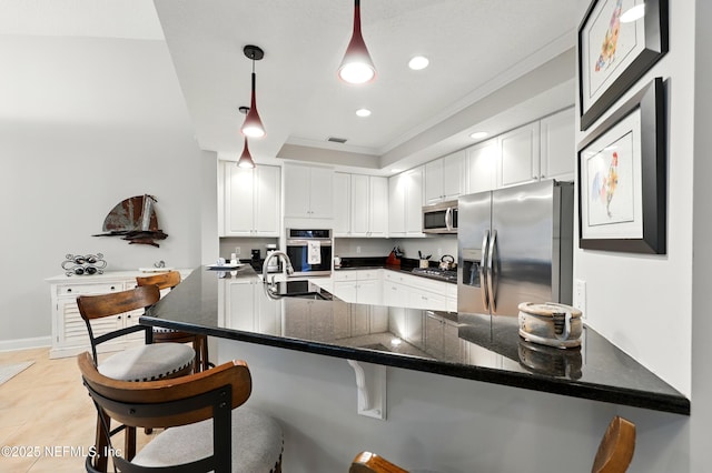 kitchen with appliances with stainless steel finishes, ornamental molding, a peninsula, white cabinetry, and a sink