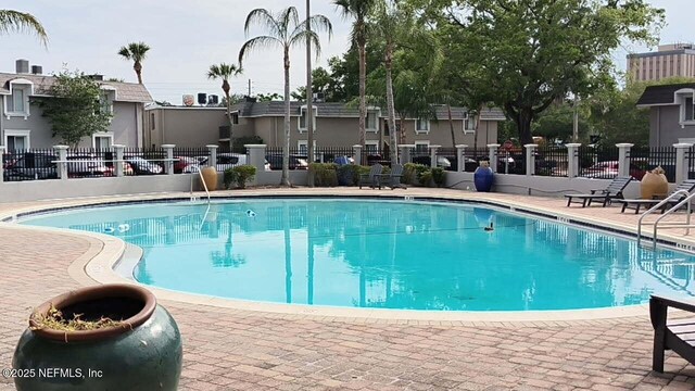 community pool featuring fence and a patio area