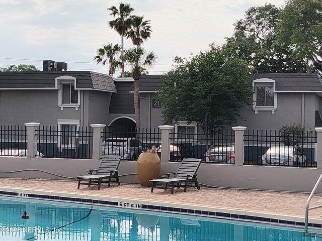 community pool featuring fence and a patio