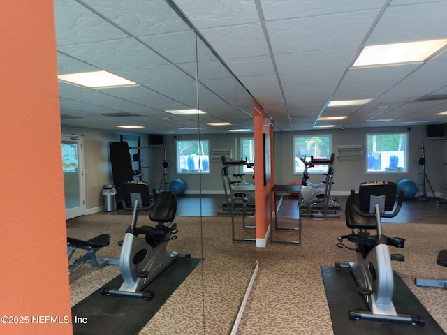 exercise room with baseboards, a paneled ceiling, and plenty of natural light