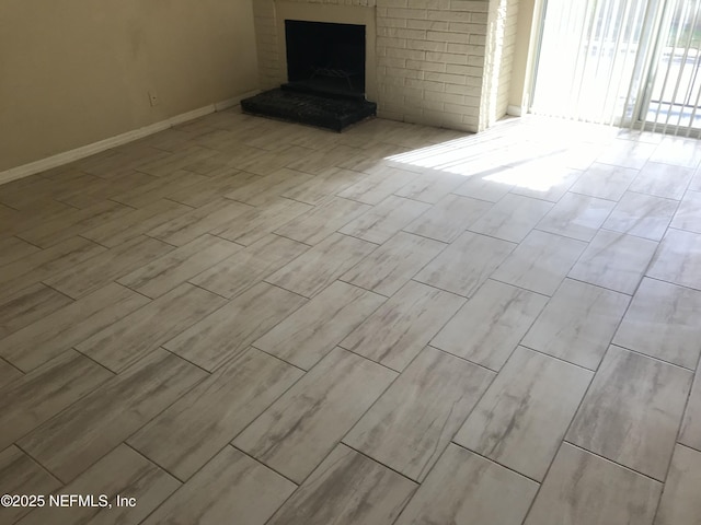 unfurnished living room with wood finish floors, a fireplace, and baseboards