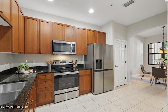 200 Paseo Terraza Unit 203, Saint Augustine, FL 32095 - kitchen with stainless steel appliances, brown cabinets, arched walkways, and recessed lighting
