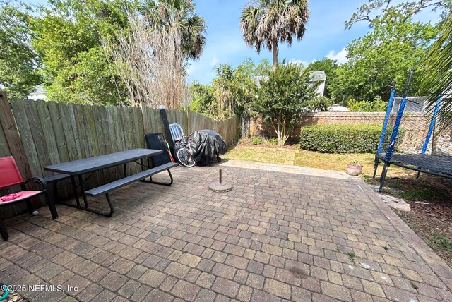 view of patio / terrace featuring a trampoline, a fenced backyard, and outdoor dining area