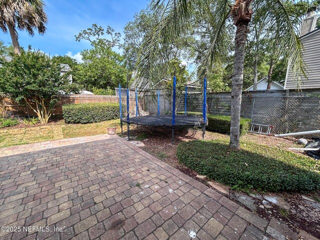 view of patio with a trampoline and a fenced backyard