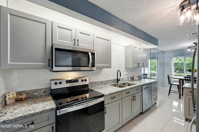 9360 Craven Rd Unit 1406, Jacksonville, FL 32257 - kitchen with stainless steel appliances, a sink, tasteful backsplash, a textured ceiling, and gray cabinets