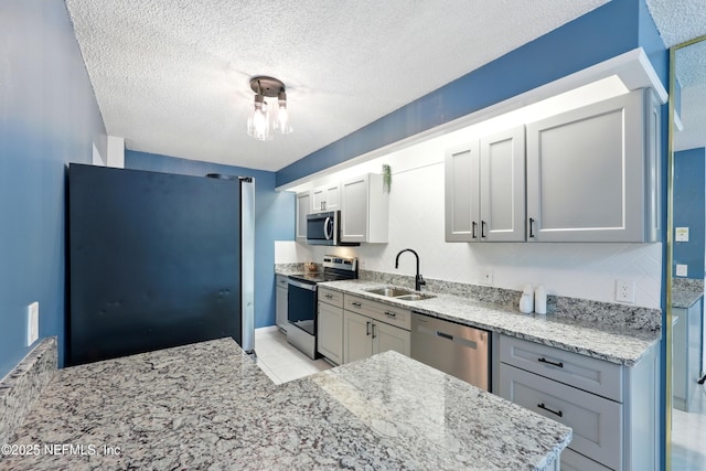 9360 Craven Rd Unit 1406, Jacksonville, FL 32257 - kitchen featuring stainless steel appliances, a sink, light stone counters, a textured ceiling, and light tile patterned floors