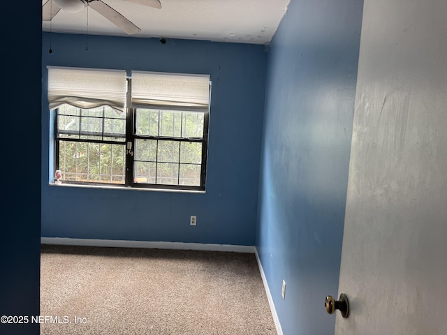 carpeted spare room with ceiling fan and baseboards