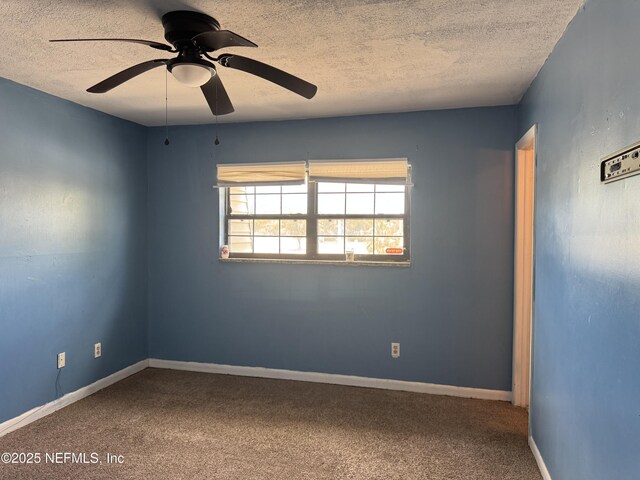 empty room with a textured ceiling, a ceiling fan, carpet flooring, and baseboards
