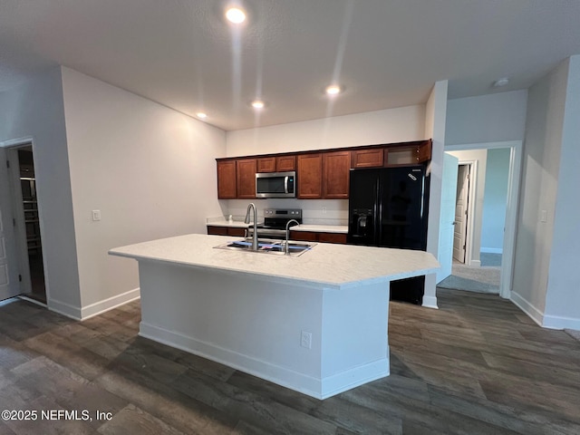 kitchen featuring appliances with stainless steel finishes, baseboards, dark wood-type flooring, an island with sink, and light countertops
