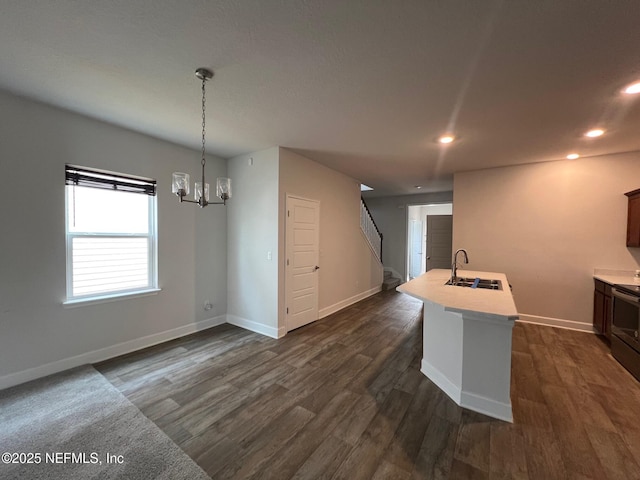 kitchen featuring light countertops, a sink, baseboards, recessed lighting, and dark wood-type flooring