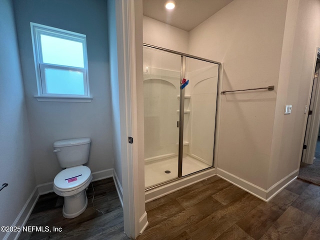 full bath with baseboards, wood finished floors, a shower stall, and toilet