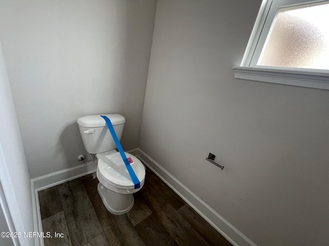 bathroom with wood finished floors, toilet, and baseboards
