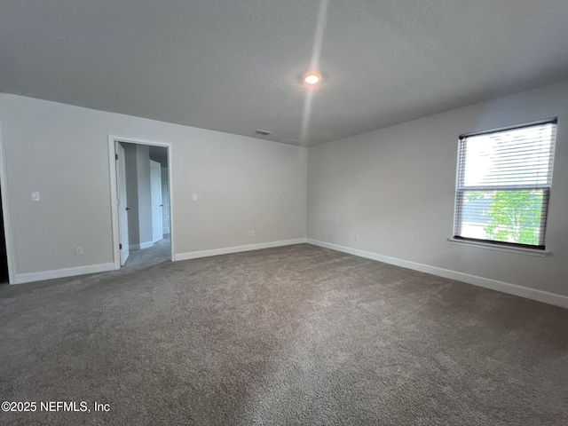 empty room featuring dark colored carpet, baseboards, and a textured ceiling