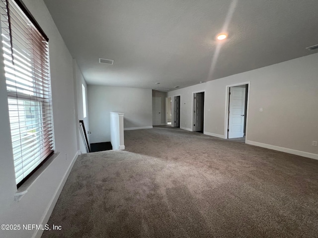 unfurnished living room featuring carpet and baseboards