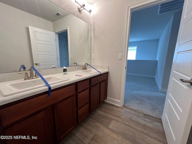 full bathroom featuring wood finished floors, double vanity, and baseboards