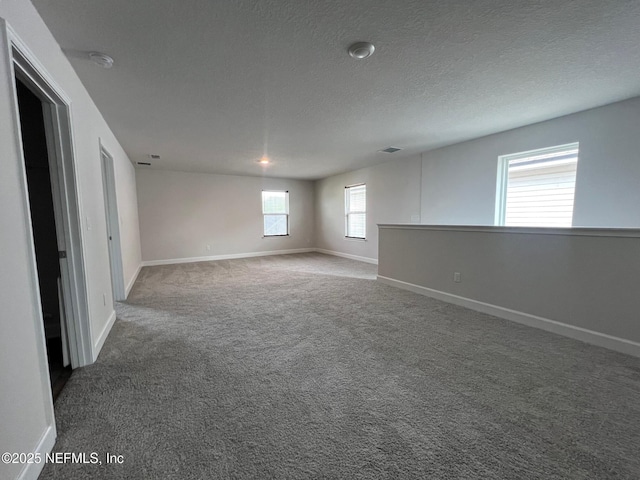 carpeted spare room featuring baseboards and a textured ceiling