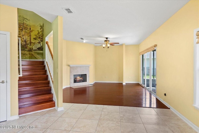 11092 Turnbridge Dr Unit 74, Jacksonville, FL 32256 - unfurnished living room featuring ceiling fan, tile patterned floors, a tiled fireplace, stairs, and baseboards