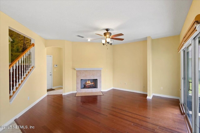 11092 Turnbridge Dr Unit 74, Jacksonville, FL 32256 - unfurnished living room featuring wood finished floors, a ceiling fan, a fireplace with flush hearth, arched walkways, and stairway