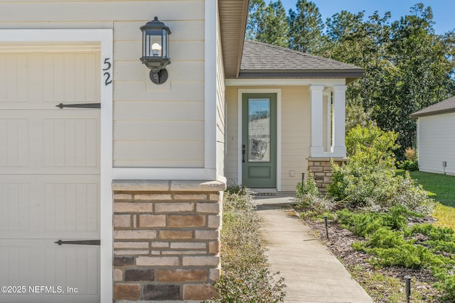 view of exterior entry with a shingled roof