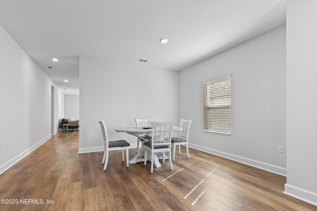 dining area with hardwood / wood-style flooring, baseboards, a textured ceiling, and recessed lighting