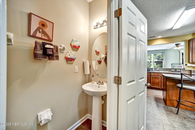 8672 Ribbon Falls Ln, Jacksonville, FL 32244 - bathroom with a textured ceiling, tile patterned flooring, a sink, a ceiling fan, and baseboards