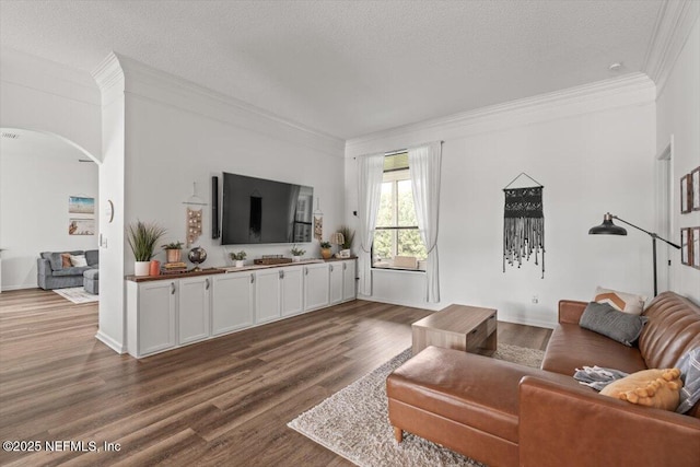 living area featuring arched walkways, crown molding, dark wood-style flooring, and a textured ceiling