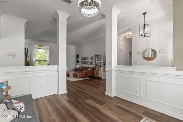 dining room featuring ornate columns, a chandelier, dark wood-style floors, a decorative wall, and a wainscoted wall